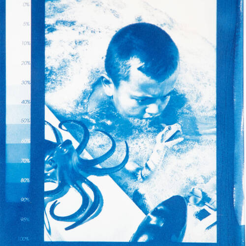 Blue cyanotype image of a young boy in the bathtub with a octopus and boat toy.